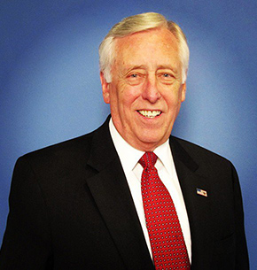 Picture of Steny Hoyer in a black suit, white button down shirt and a red tie in front of a blue background.