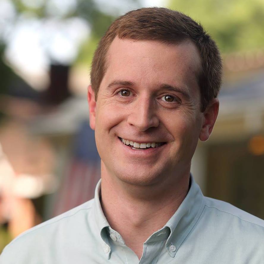 Dan McCready standing outside wearing a light green button down shirt and smiling