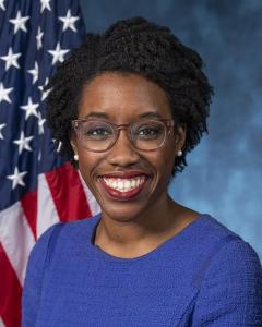 Laura Underwoode in front of an American flag wearing a blue dress in glasses
