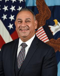 Gil Cisneros standing in front of the American flag