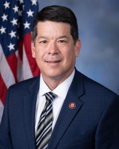 Rep. Cox standing next to the American Flag