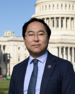 Andy Kim standing in front of the Capitol building in a blue suit, blue shirt, blue tie