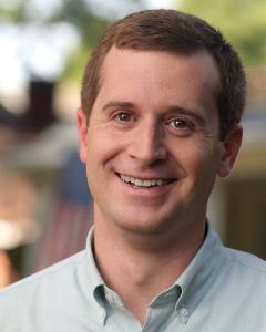 Dan McCready standing outside wearing a light green button down shirt and smiling